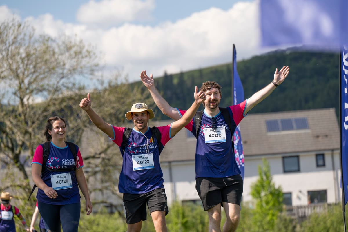 A group of hikers smiling at the camera, with their hands in the air.