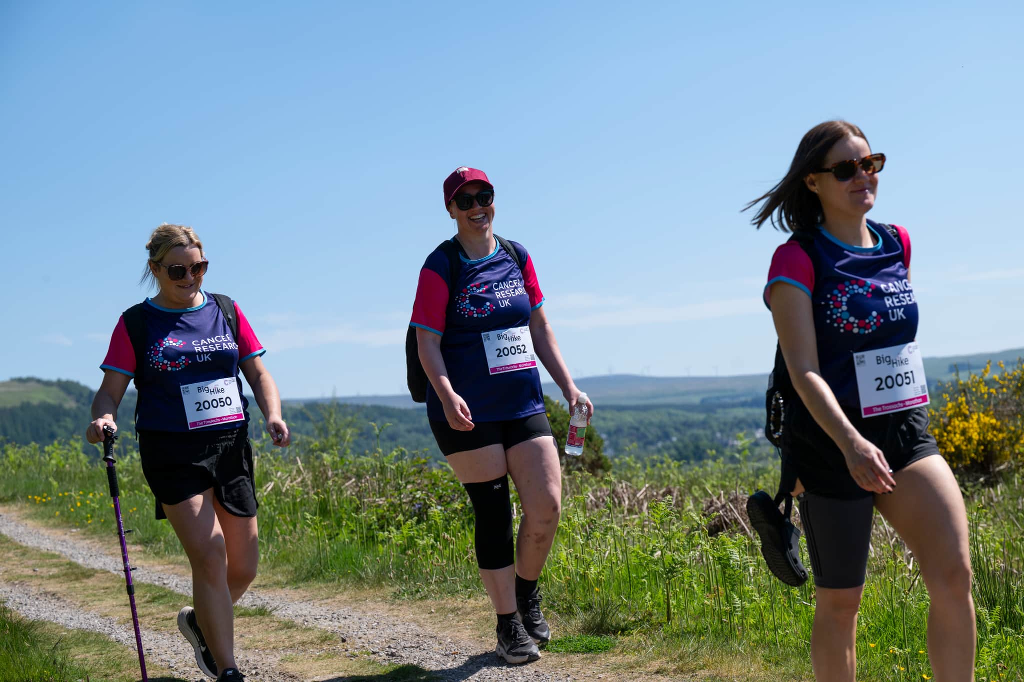 Three hikers walking along the countryside.