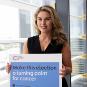 Larissa holding a poster that reads 'Make this election a turning point for cancer'