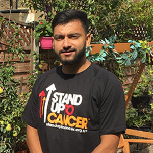 Nish outside wearing a Stand Up to Cancer top