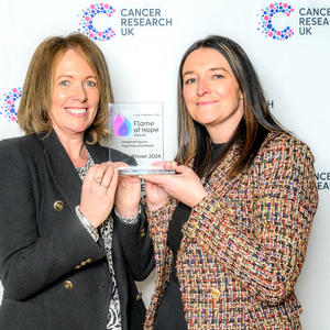 Two people holding a Flame of Hope trophy