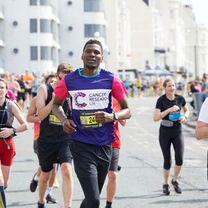 Man running in Brighton marathon wearing CRUK top