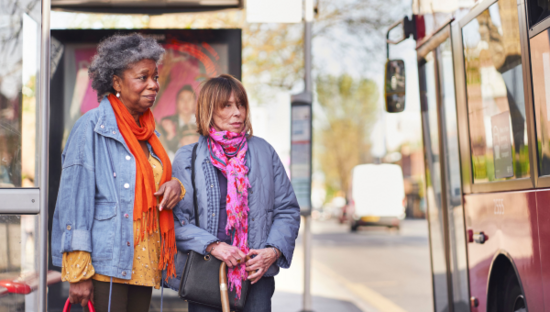 Two people stood at a bus stop, waiting to board. Two people stood at a bus stop, waiting to board.