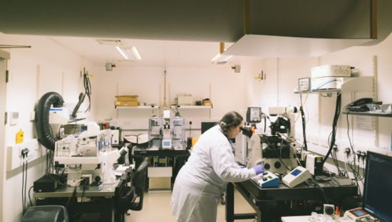 Researcher in a lab looking into a microscope