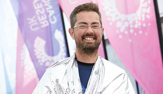 Man in front of Cancer Research UK flags after a swim