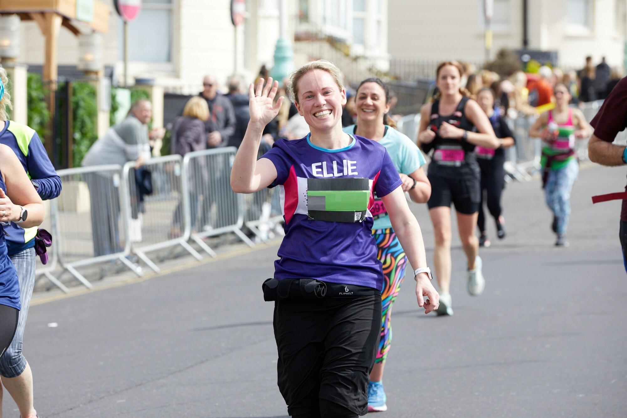 Girl smiles and waves as she runs for Cancer Research UK