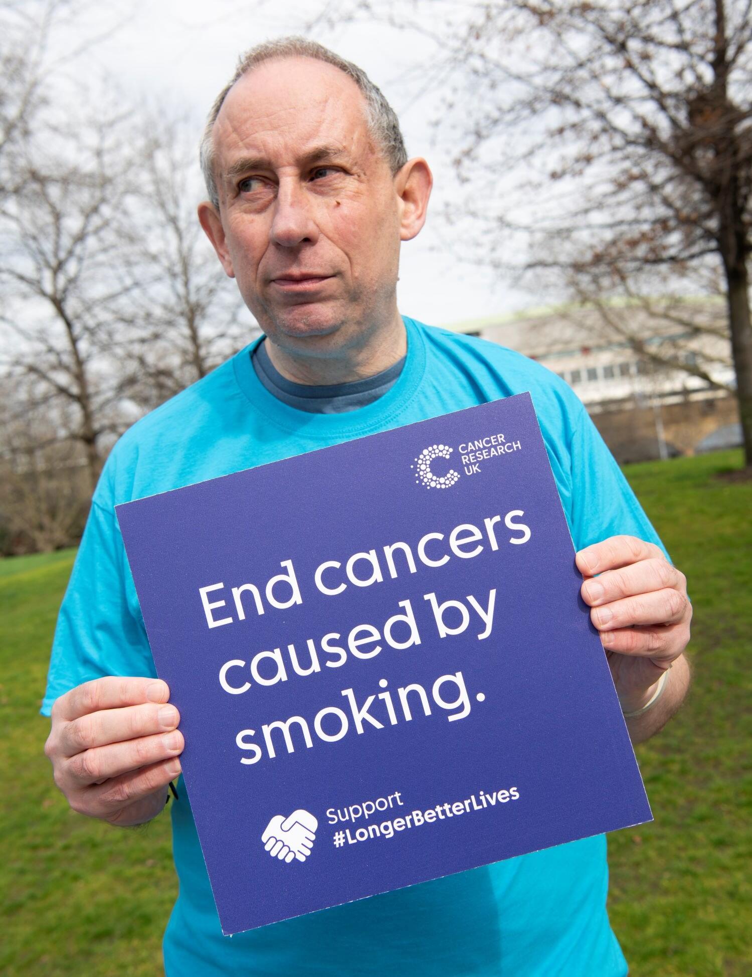 Campaigner holding a sign that reads 'Help end cancers caused by smoking'