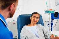 A woman sat in a hospital chair with a doctor