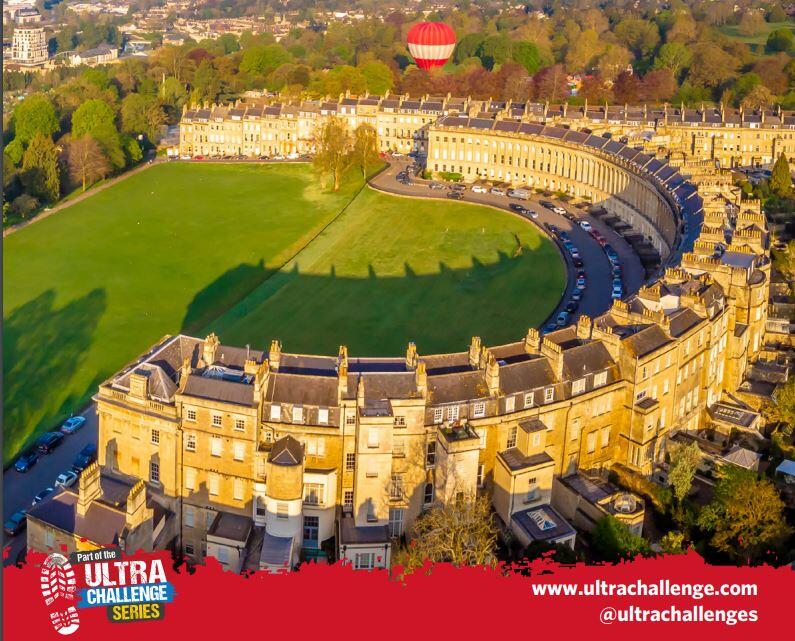 Aerial photo of the Royal Crescent, Bath, on a sunny day with a hot air balloon in the sky. 