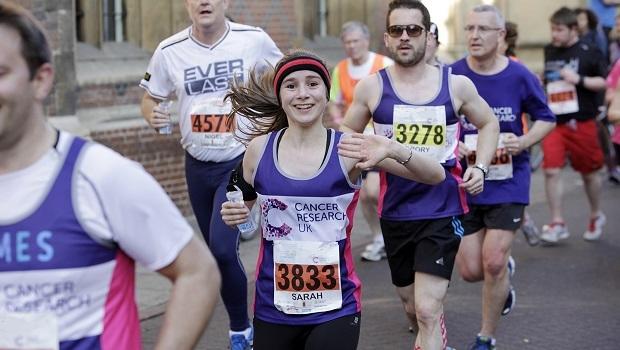 Girl smiles and waves as she runs for Cancer Research UK