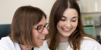 Two women researchers working together, they are both smiling.