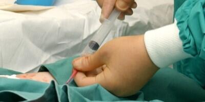 Shows the hands of a healthcare professional using a syringe, treating a patient.