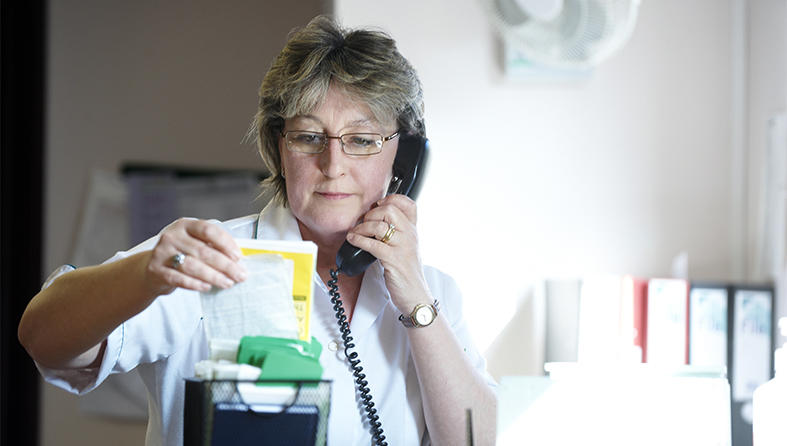 Nurse on the phone referring to patient notes