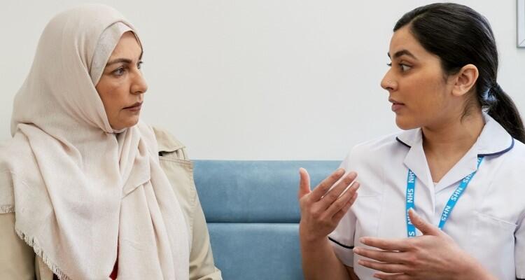 Two people in a medical setting in discussion; one appears to be a patient and the other a healthcare practitioner.