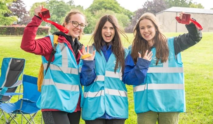 Three female volunteers cheering at race for life