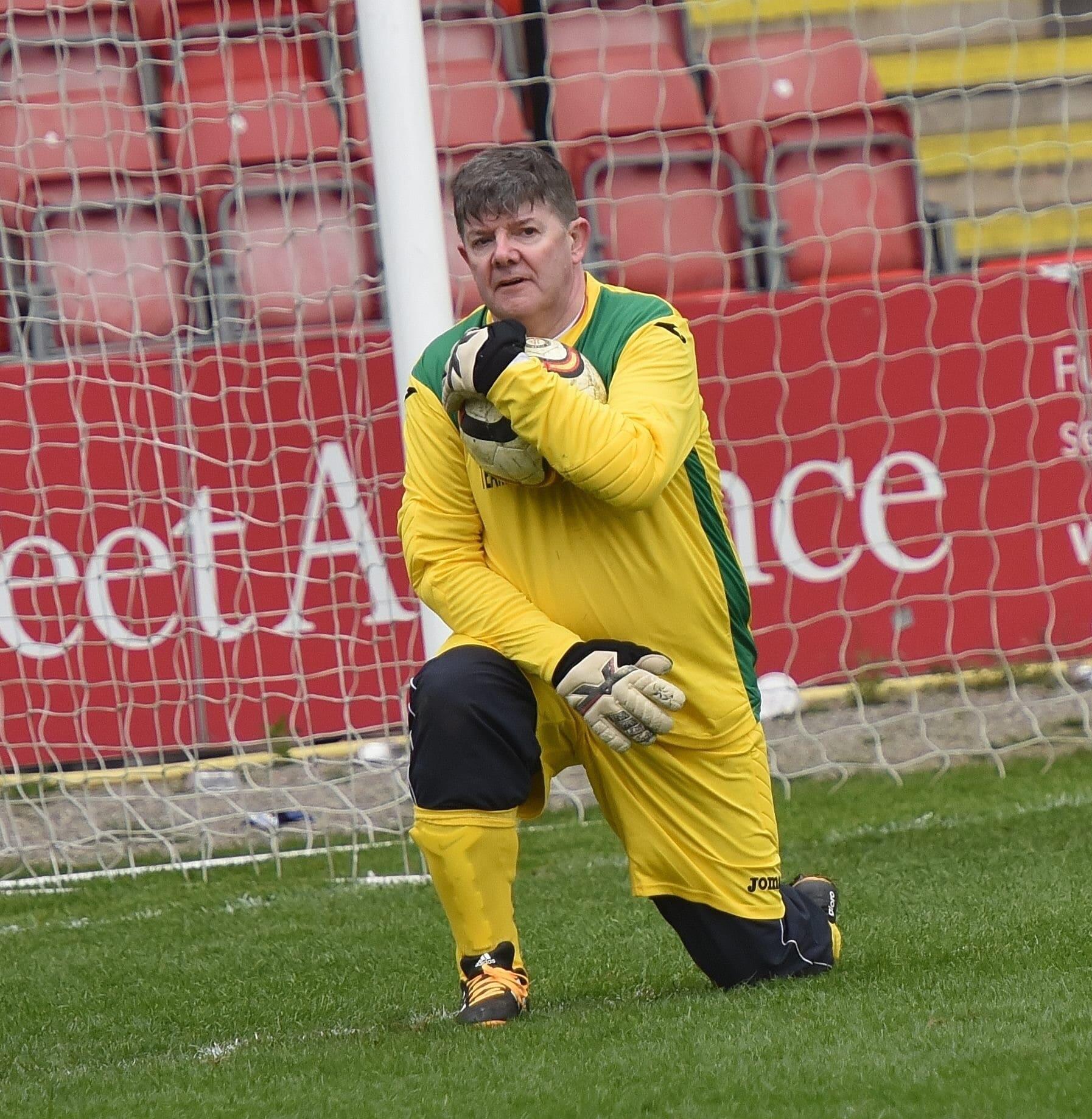 Image of Ian holding a football, kneeling in front of a goal