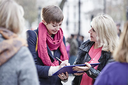 Two people fill out a survey on the street