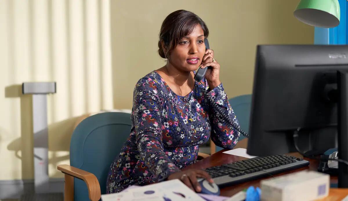 GP on the phone in front of a computer screen
