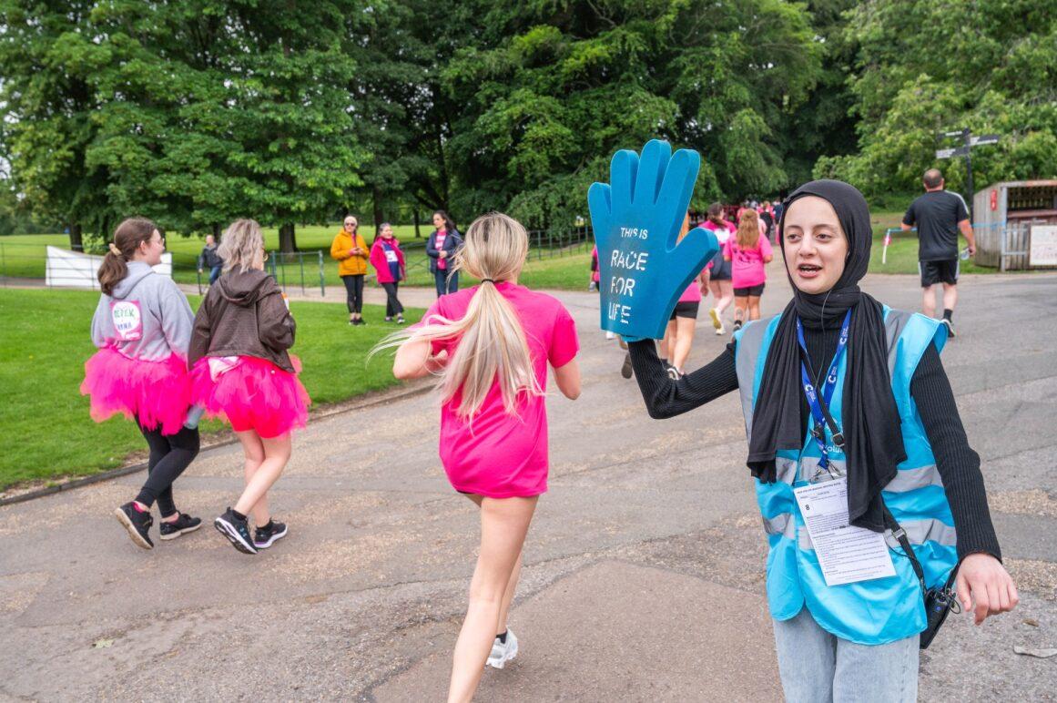 Volunteer wearing foam glove cheering on race for life participants