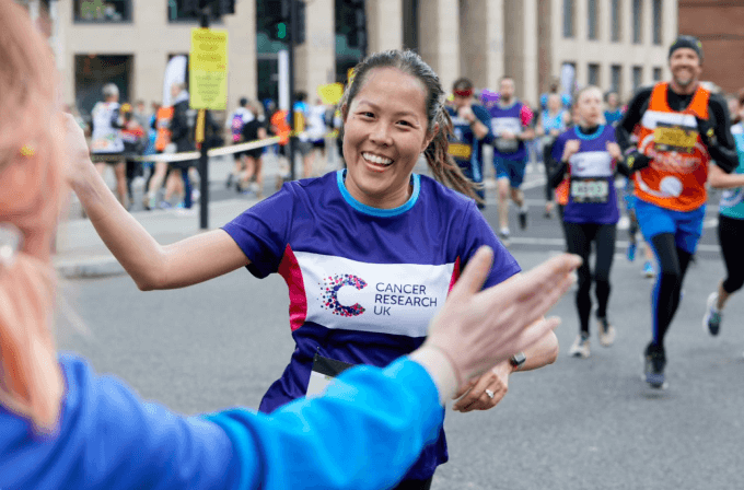 Smiling woman high fives a supporter in the crowd as she runs past