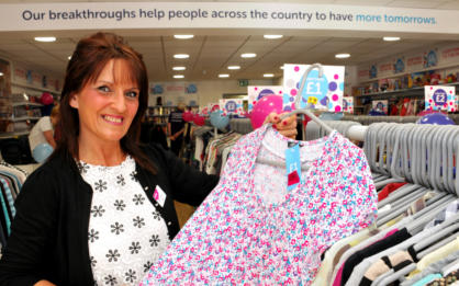 A Cancer Research UK shop manager holding up a piece of clothing