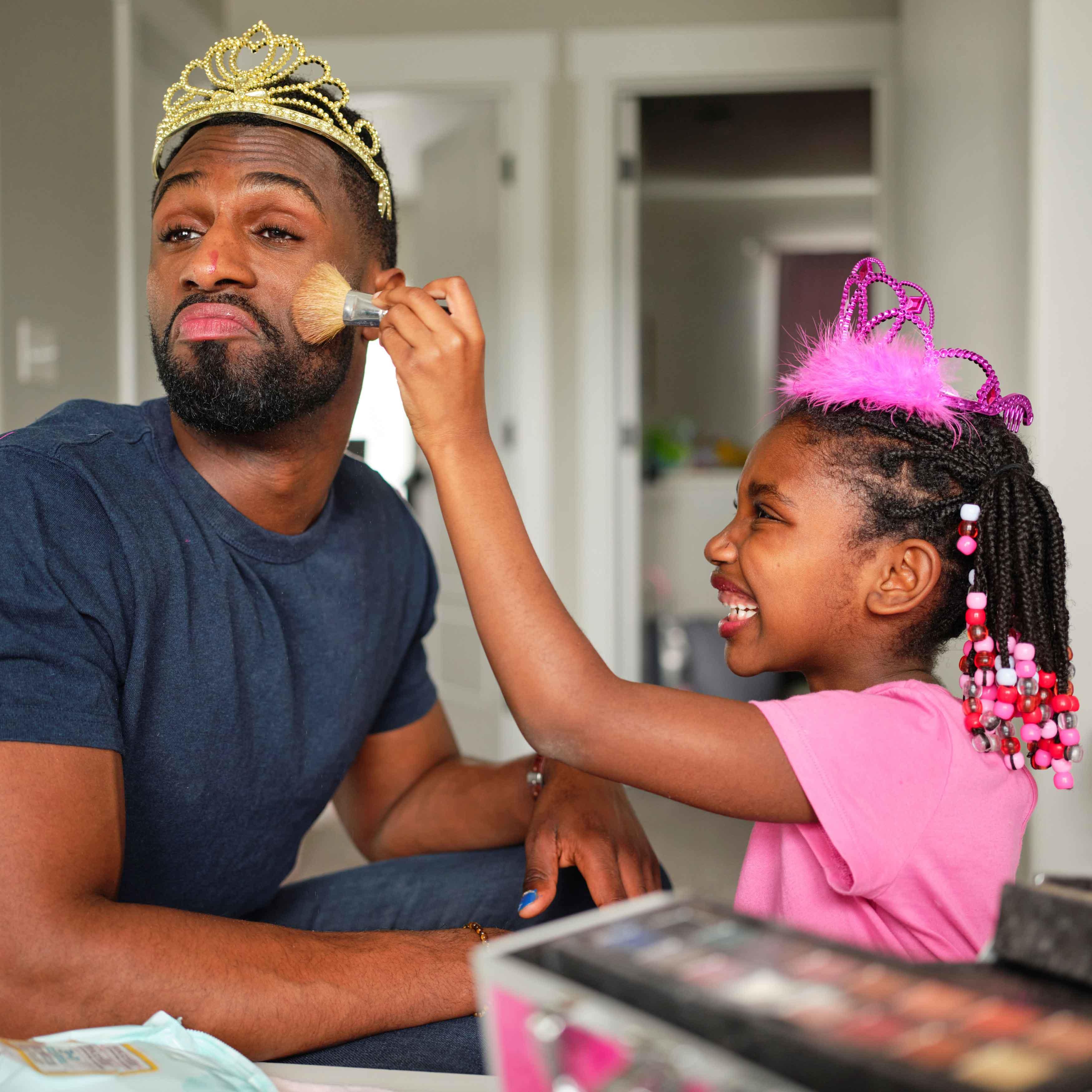 A man letting his daughter put make up on his face