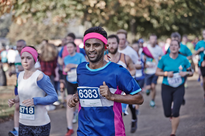 A man running in CRUK colours, with a pink headband. 