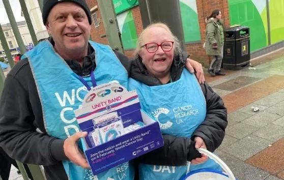 Two volunteers with fundraising buckets outside