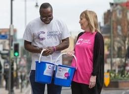 Black man and white woman collecting money in buckets on street