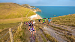 Runners on cliffside running Jurassic coast challenge 