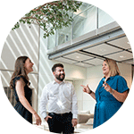 A photo of three people chatting and smiling in an office