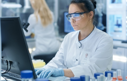 Female scientist sat at a computer screen in a lab