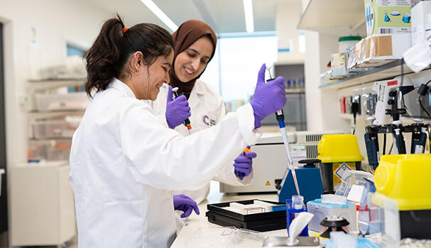 Two researchers smiling and pipetting in a lab