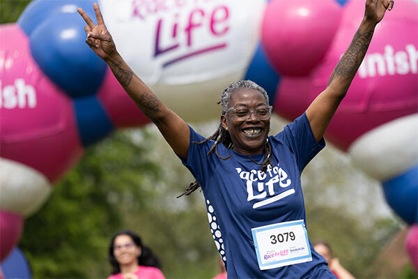 Woman smiling holding up a peace sign 