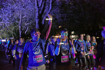 Group of Shine London participants smiling, wearing glow sticks, as they take on the night walk