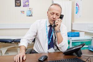 GP sat at his desk talking on the phone.