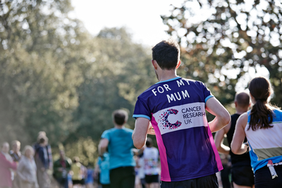 Male runner, wearing a CRUK runner vest, taking part in the Royal Parks Half Marathon 