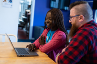 Two volunteers sat down looking at a laptop together