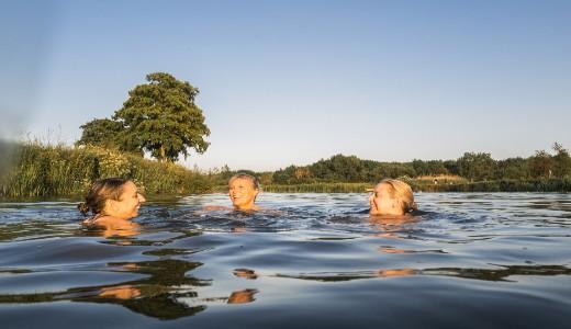 Three women swimming together in a lake