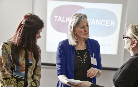 Women speaking in front of a 'Talk Cancer' sign