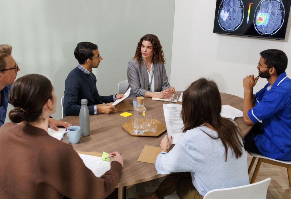 Drs sitting around a table looking at a scan on a tv screen 