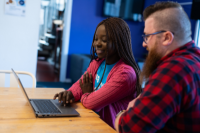 Two people sat looking at a laptop
