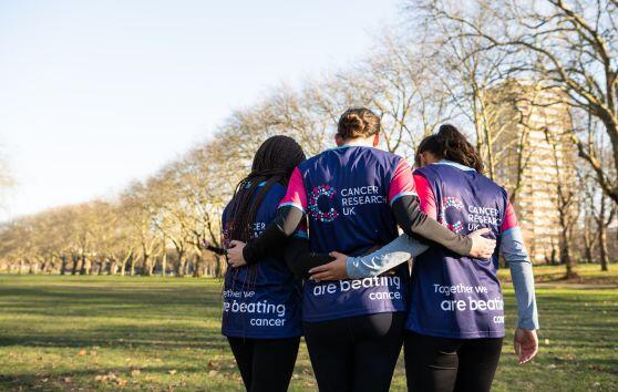 Three people with their arms round each other, walking away from the camera