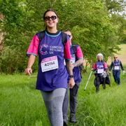 A Big Hike participant wearing a CRUK tshirt walking in a green field